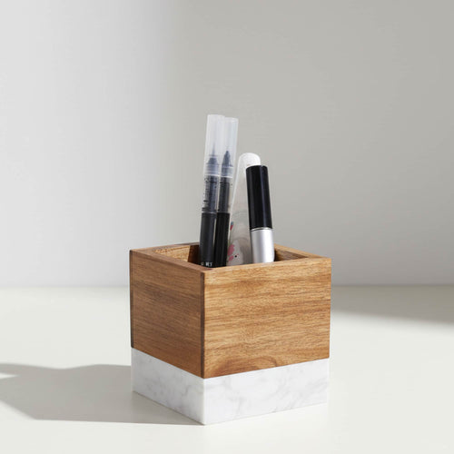 Marble and acacia wood pen pencil holder filled with pens on desk